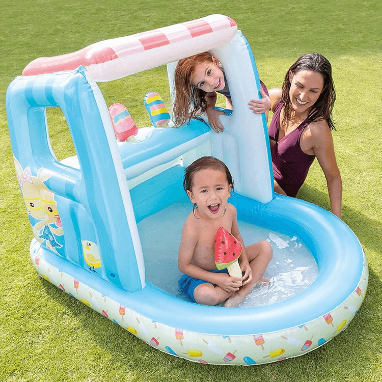 A mother and two children playing outdoors in the water-filled Intex Gelato kiddie pool with canopy.