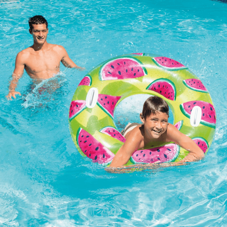 A boy swimming happily in a pool using the large Intex Watermelon inflatable float.