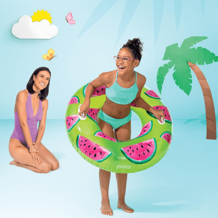 A girl playing with the Intex Watermelon pool tube while a woman watches nearby.