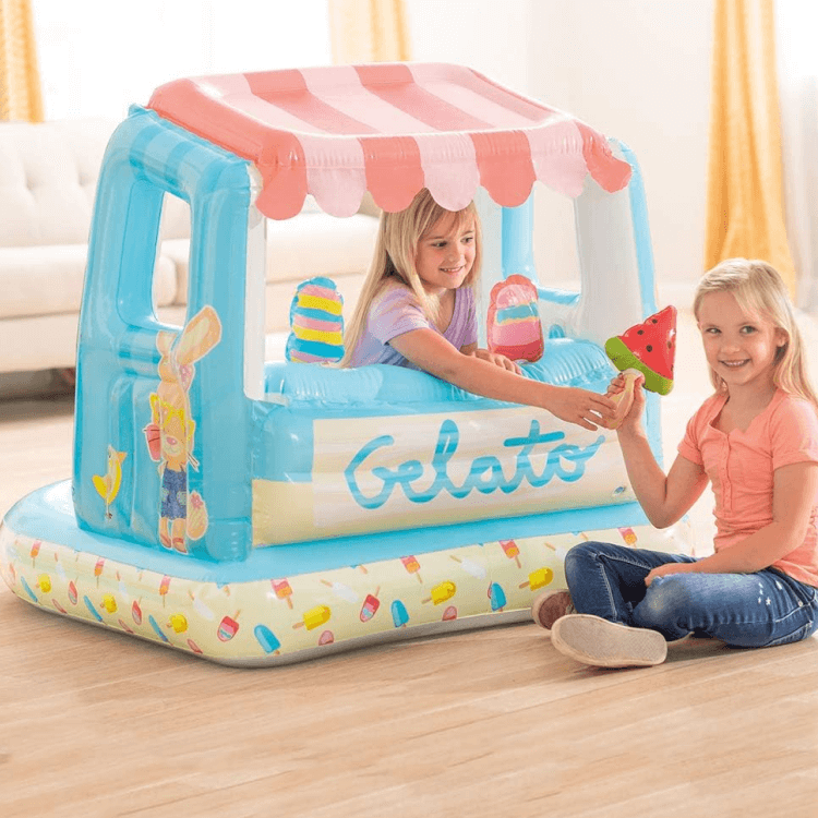 Two young girls playing indoors using the Intex Gelato inflatable as a dry playhouse toy.